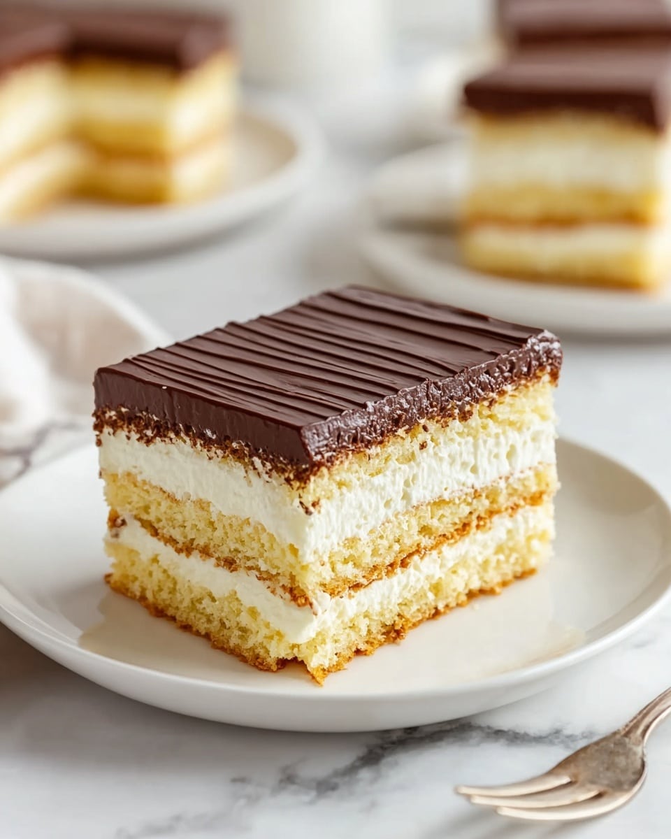 A square slice of layered cake sits on a white plate over a white marbled surface. The cake has four layers: starting from the bottom, a light golden sponge layer, then a thick creamy white layer, followed by another golden sponge layer, topped with another thick creamy white layer, and finished with a smooth, dark chocolate layer on top that has slight horizontal ridges. In the background, more pieces of the same cake are slightly out of focus on another white plate. Photo taken with an iphone --ar 4:5 --v 7