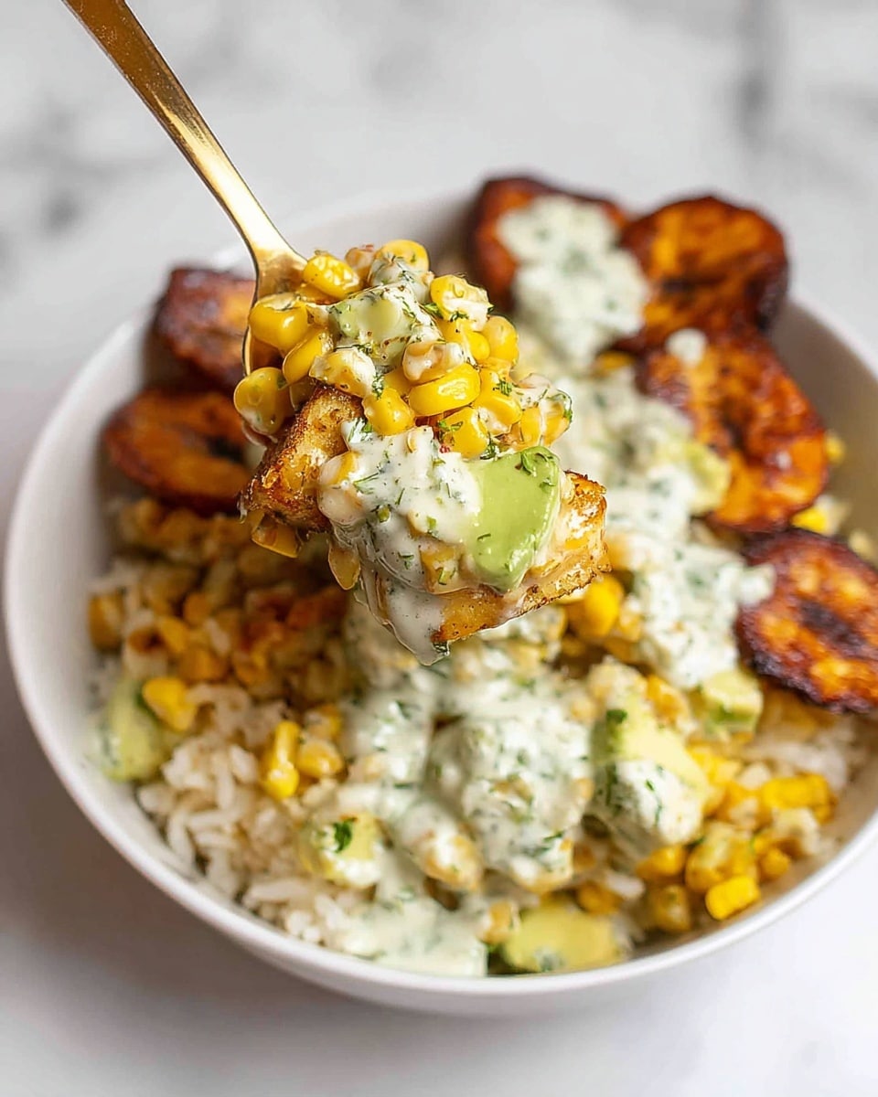 The image shows a white bowl filled with a colorful dish made of several layers. The base layer is light yellow to white rice, topped with roasted, dark brown, crispy plantain slices scattered around. On top, there is a generous layer of bright yellow corn kernels mixed with small pieces of pale green avocado. The whole dish is covered in a creamy white sauce with green specks, likely herbs, that drips slightly onto the sides. A gold spoon holds a close-up bite with a mix of all these ingredients, showing the thick and creamy texture of the sauce coating the corn, avocado, and plantain. The bowl is placed on a white marbled textured surface. photo taken with an iphone --ar 4:5 --v 7