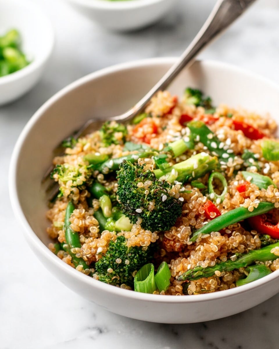 A white bowl filled with a colorful quinoa salad showing one main layer of cooked quinoa grains mixed with bright green broccoli florets, green beans, chopped green onions, and small pieces of red bell pepper scattered throughout; white sesame seeds sprinkled over the top add texture and detail, with a silver fork resting inside the bowl. The bowl sits on a white marbled surface with blurred white bowls in the background. photo taken with an iphone --ar 4:5 --v 7