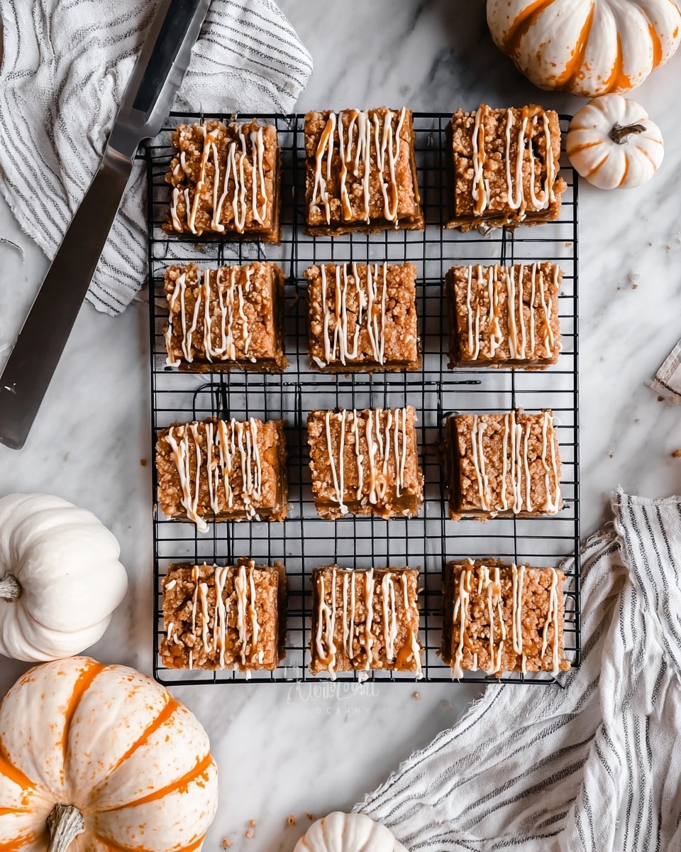 The image shows sixteen square dessert bars arranged neatly in rows on a black wire cooling rack. Each bar has three layers: a bottom light brown layer, a middle darker brown layer, and a crumbly, textured top layer in light brown. On top, there are irregular drizzles of caramel-colored and creamy white sauces, adding visual contrast. The rack is placed on a white marbled surface with a white and black striped cloth and a large silver knife to the top left. Around the rack, there are small white pumpkins and one striped pumpkin, adding a cozy autumn feel. photo taken with an iphone --ar 4:5 --v 7