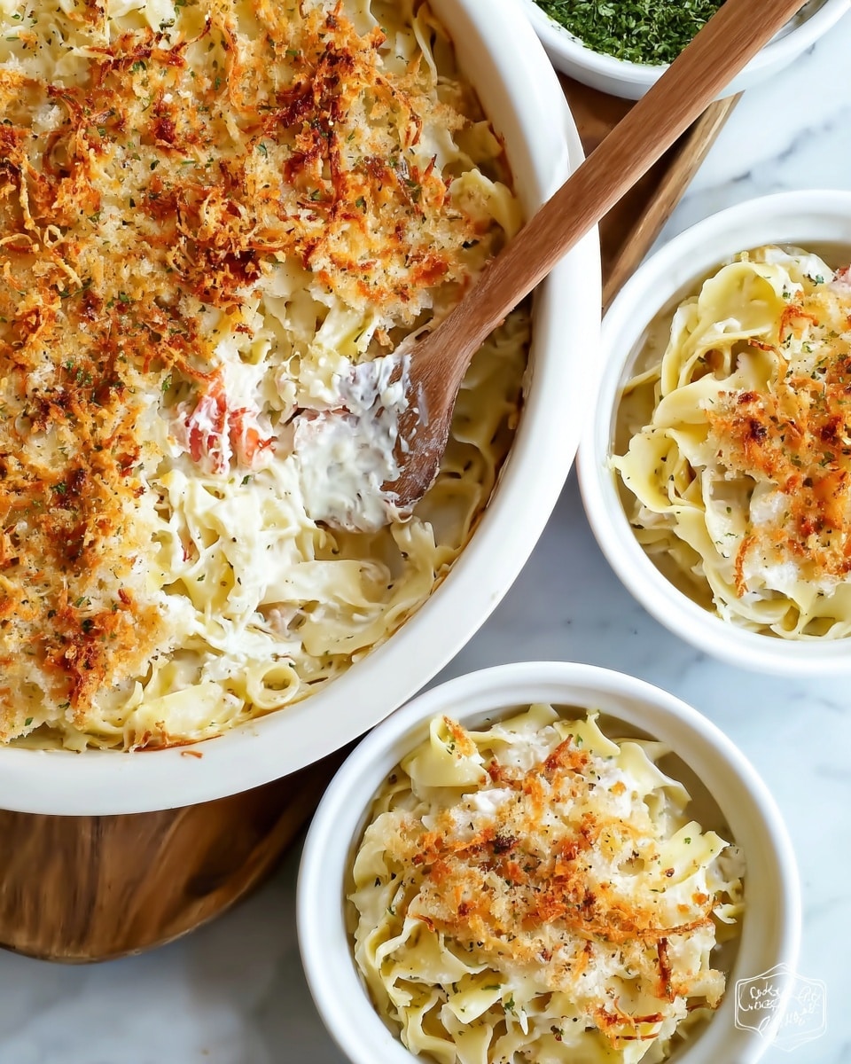 The image shows a white dish filled with layers of creamy baked pasta. The bottom layer is wide, pale yellow noodles. On top of the noodles is a thick layer of white creamy sauce with small bits of red mixed in. The top layer is golden brown from baked cheese or breadcrumbs with a slightly crispy texture. Next to the large dish are two smaller white bowls with the same layered pasta. A wooden spoon is resting in the large dish, pressing lightly on the baked top layer. The whole scene is set on a white marbled surface. Photo taken with an iphone --ar 4:5 --v 7