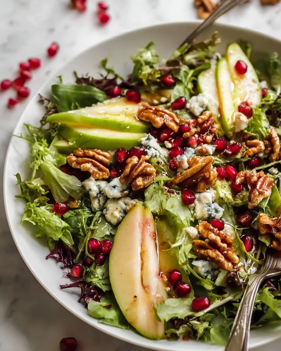 A fresh salad is shown in a white bowl on a white marbled surface. The base layer consists of mixed green leaves with different textures, including curly and leafy varieties. On top, there are slices of creamy green avocado and thin slices of pale pear. Bright red pomegranate seeds are scattered throughout, adding vibrant spots of color. Chunky walnuts are spread over the salad, glistening slightly, likely from a light dressing. Small crumbles of blue cheese appear dotted around the salad's surface, adding a rich and creamy texture. A silver fork rests inside the bowl, slightly visible among the greens. photo taken with an iphone --ar 4:5 --v 7