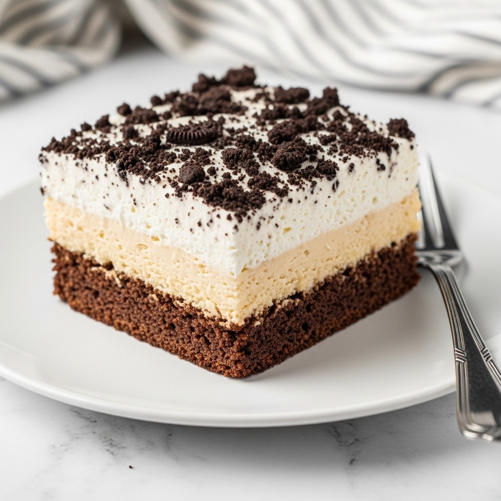 The image shows a square piece of layered cake on a white plate. The cake has three distinct layers: a dark brown crumbly base layer, a creamy light beige middle layer, and a thick white creamy top layer with crushed dark cookie crumbs sprinkled over it. The texture looks soft and moist, with the cookie crumbs adding a rough contrast on the smooth creamy top. A silver fork is placed on the right side of the plate, and the background is a white marbled surface with a striped cloth slightly blurred in the back. photo taken with an iphone --ar 4:5 --v 7
