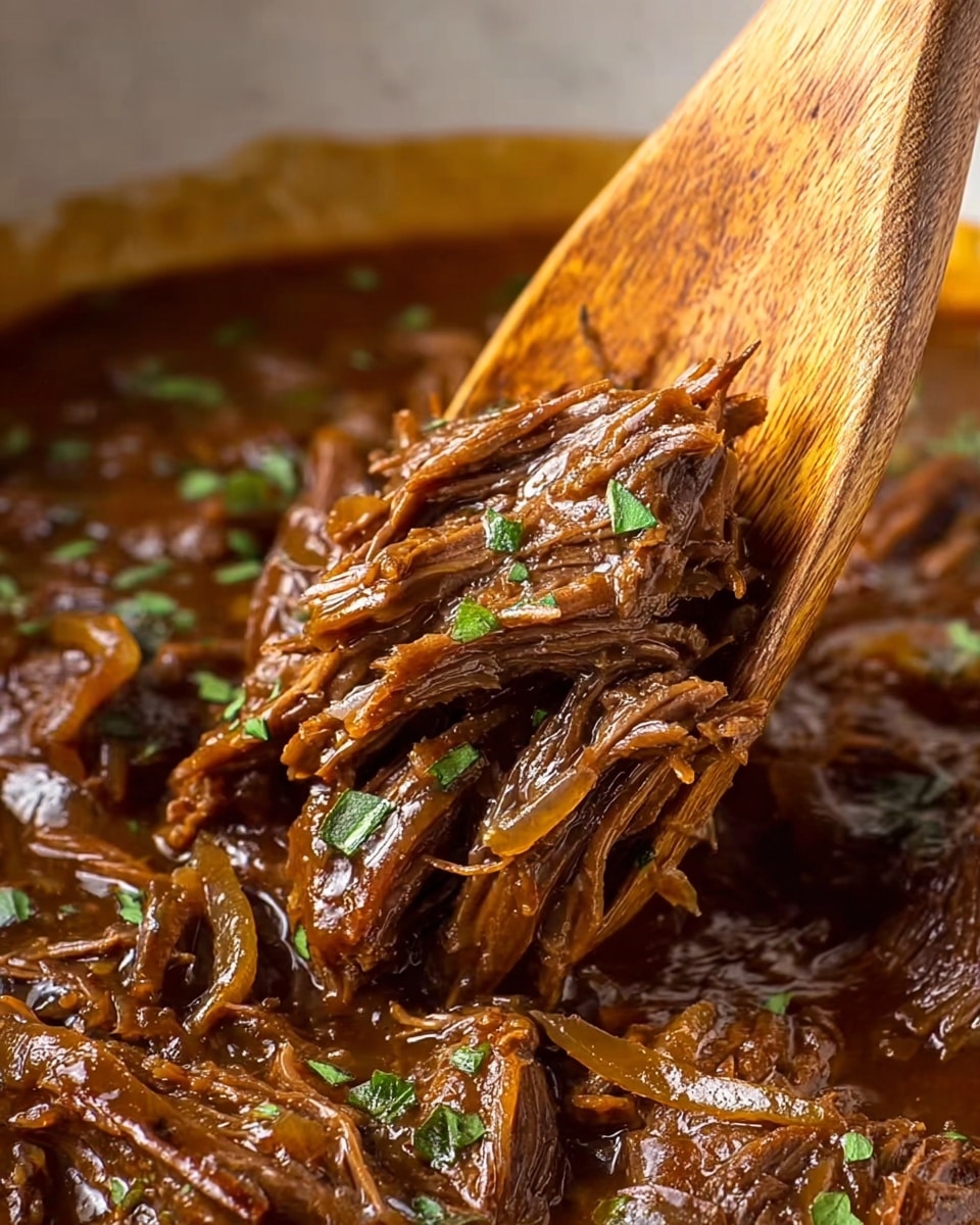 A close-up photo showing a wooden spoon lifting shredded beef cooked in rich brown gravy with translucent cooked onions mixed in, garnished with small green herb leaves scattered on top and within the saucy meat. The beef appears tender with strands easily pulled apart, coated in a shiny, thick sauce. The background shows more beef and sauce against a white marbled texture. photo taken with an iphone --ar 4:5 --v 7