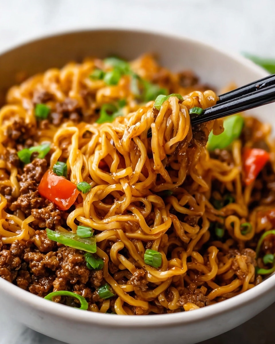 A close-up view of a bowl filled with cooked yellow noodles mixed with small pieces of brown ground meat and topped with green chopped scallions and thin orange carrot slices, with a pair of metal chopsticks lifting a tangled bite from the bowl. The noodles look glossy and coated in sauce, creating a shiny texture. The bowl is white and contrasts with the colorful food inside, all placed on a white marbled surface. Photo taken with an iphone --ar 4:5 --v 7