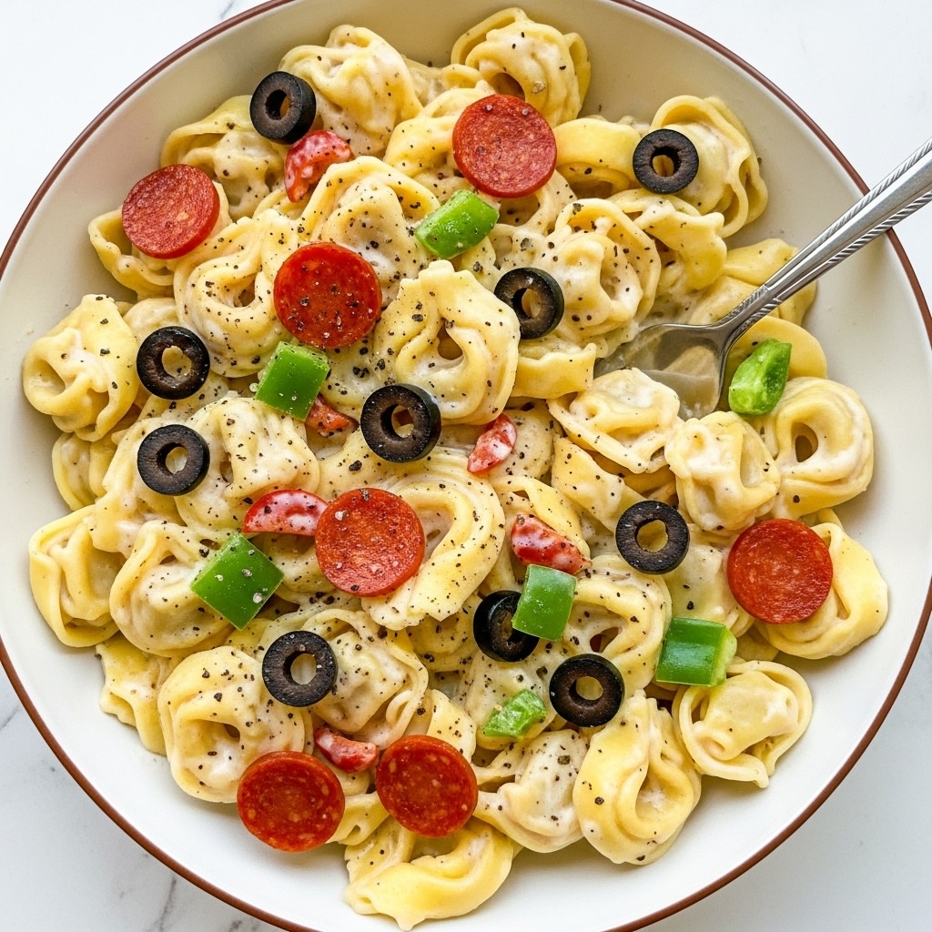 A close-up of a wooden bowl filled with pasta salad, showing a mix of three layers: at the base is curly yellow pasta with a smooth texture, scattered with bright green peas and bits of orange carrot. The middle layer shows round slices of pinkish-red sausage evenly spread, mixed with dark purple black olives and small cubes of white feta cheese that have specks of black pepper. At the top, there is a light sprinkle of grated parmesan cheese and finely chopped fresh green herbs, adding a fresh look throughout the dish. The bowl is set against a white marbled texture background. photo taken with an iphone --ar 4:5 --v 7